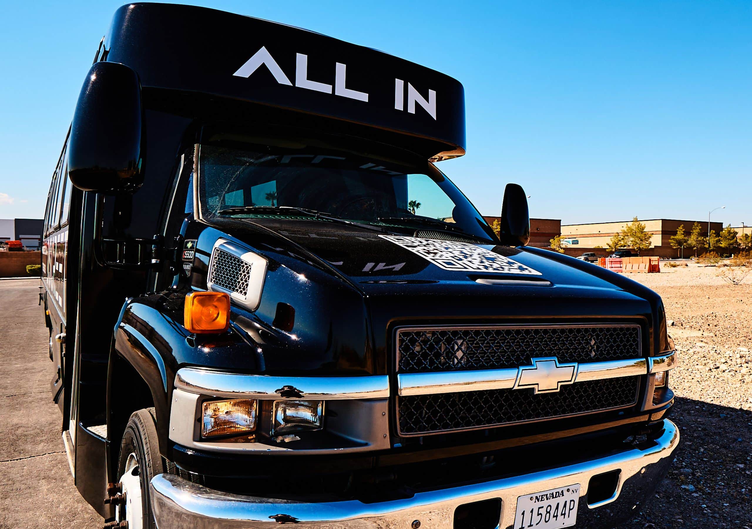 All In 30-passenger Las Vegas party bus with chrome grille and Nevada plates under casino lights, ideal for group events.