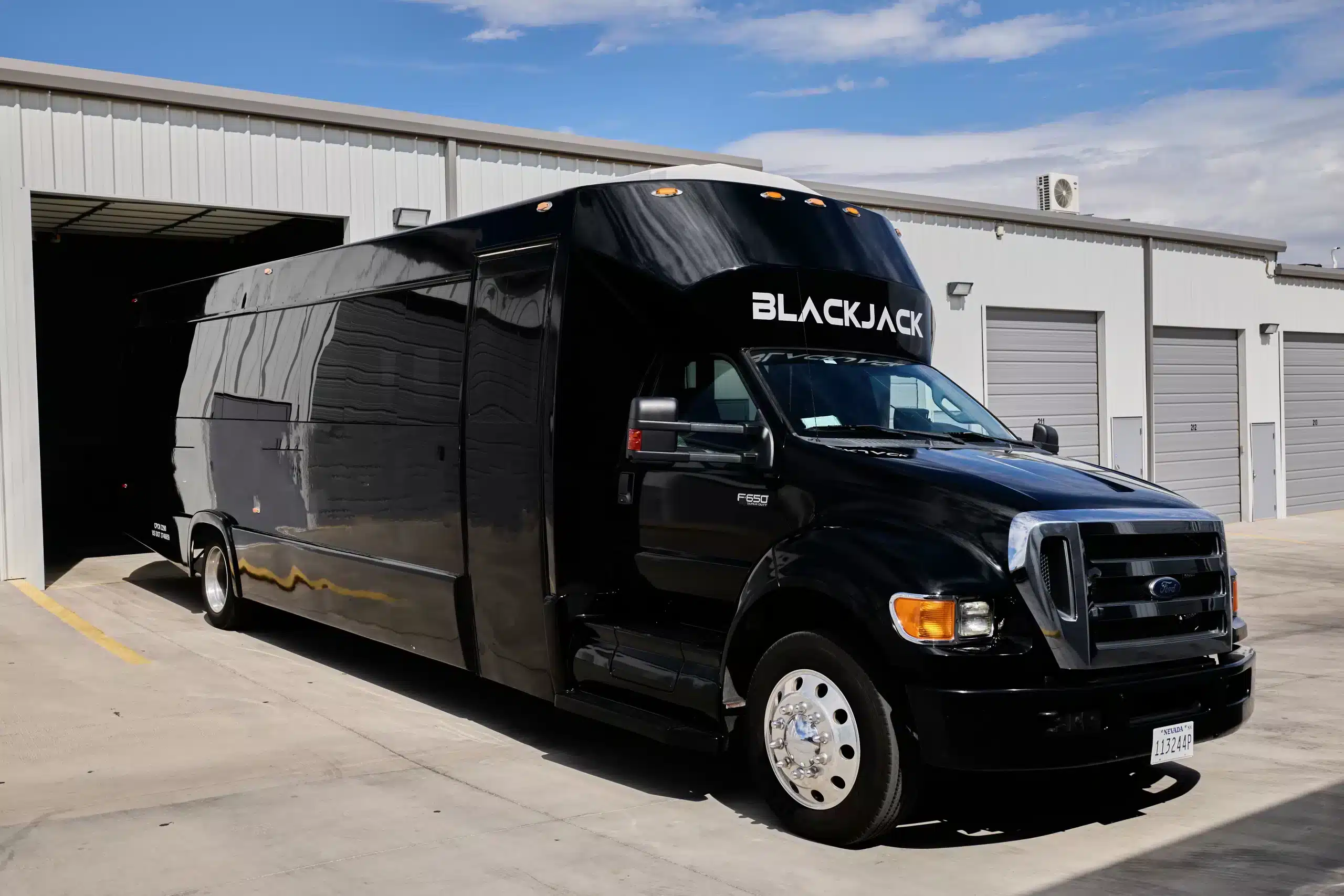 40-passenger Blackjack Las Vegas party bus parked at an industrial depot — perfect for nightlife groups and event transportation.